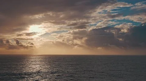 Dramatic sunrise over the ocean. A ray of the sun breaks through the clouds Stock Photos