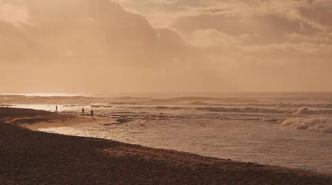 Dramatic sunrise over the ocean. Sandy coast of Oahu island, Hawaii. People walk Stock Photos