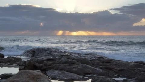 Dramatic sunrise over ocean waves crashing on rocky shore. Video stock 333166260