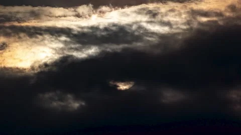 Dramatic sunrise with sun peeking through thick dark storm clouds in the sky Stock-Footage 342327770
