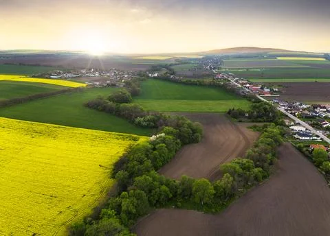 Dramatic sunset above agriculture fields and trees with village, drone view Stock-Fotos