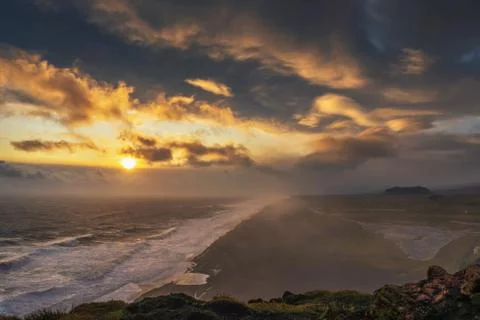 Dramatic sunset above a black beach viewed from Dyrholaey viewpoint in Iceland Foto stock