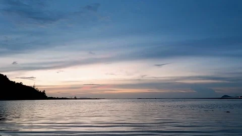 Dramatic sunset and blue sky with silhouette of mountain over calm water sea  Stock-Footage 94386142