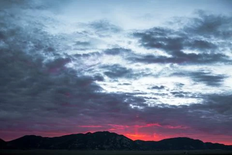 Dramatic sunset and mountain range under dramatic clouds Stock Photos