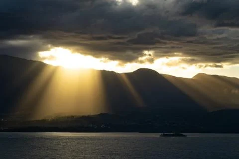 Dramatic sunset with beautiful rays over the mountains and the sea Stock Photos