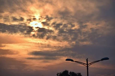 Dramatic sunset behind clouds and streetlights Stock Photos