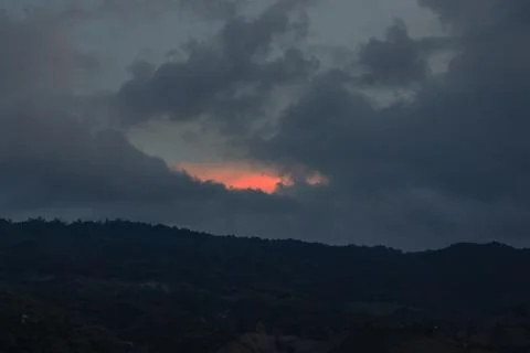 Dramatic Sunset Behind Dark Clouds Over Hills Stock Photos