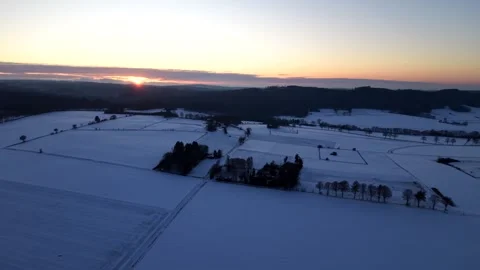 Dramatic sunset behind forest hills on snowy winter evening in USA. Aerial Stock Footage 328695554