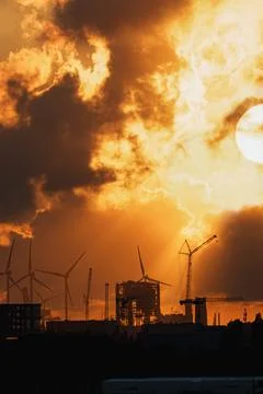 Dramatic Sunset Behind Industrial Skyline and Wind Turbines Foto stock