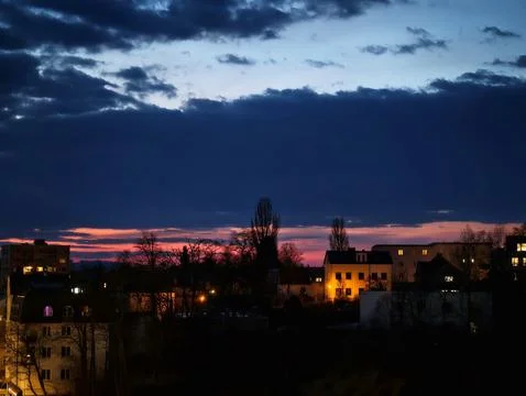 Dramatic Sunset Casting Shadows Over City Roofs Beneath Colorful Clouds And.. Stock Photos