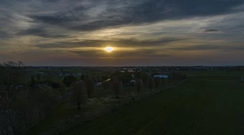 Dramatic Sunset Casting A Warm Glow Over A Rural Landscape With Silhouetted.. Foto stock