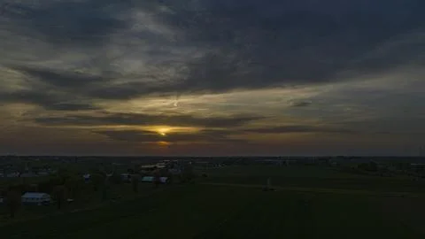 Dramatic Sunset Casting A Warm Glow Over A Rural Landscape With Silhouetted Stock Photos