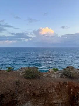 Dramatic sunset clouds illuminate the vast ocean from a rugged cliff edge Foto stock