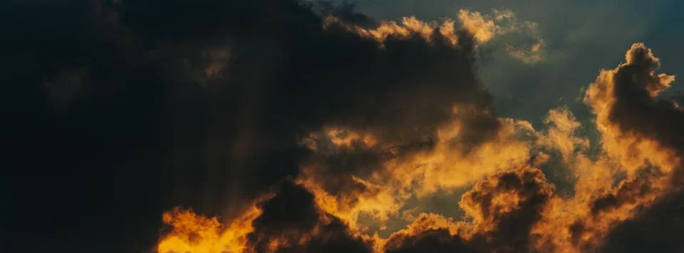 Dramatic sunset clouds illuminated by golden light with dark storm clouds c.. Stock Photos