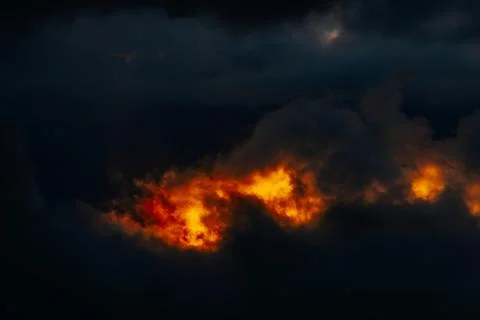 Dramatic sunset clouds illuminated by orange and yellow hues against a dark.. Stock Photos