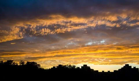 Dramatic sunset clouds over city skyline silhouette Foto stock