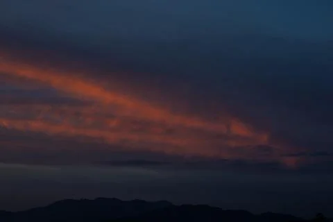 Dramatic Sunset Clouds Over Dark Mountains Stock Photos