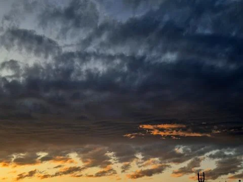 Dramatic sunset clouds over horizon with warm orange glow Stockfoto's
