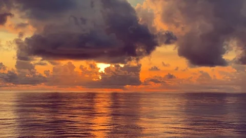 Dramatic sunset clouds over the ocean with vibrant orange reflections on th.. 動画素材 338282754