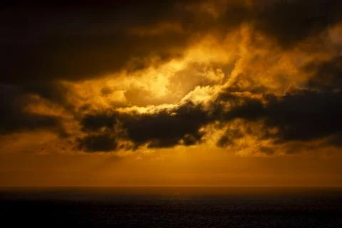 Dramatic sunset clouds over the ocean with golden light rays breaking through Fotos de archivo