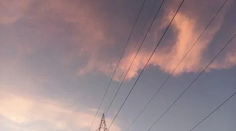 Dramatic sunset clouds with power lines and electrical cables in the evening sky Stock Photos