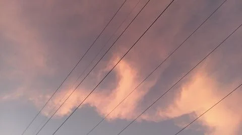 Dramatic sunset clouds with power lines and electrical cables in the evening sky Stock Photos