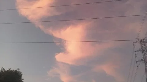 Dramatic sunset clouds with power lines and electrical cables in the evening sky Stock Photos