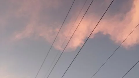 Dramatic sunset clouds with power lines and electrical cables in the evening sky Stock Photos