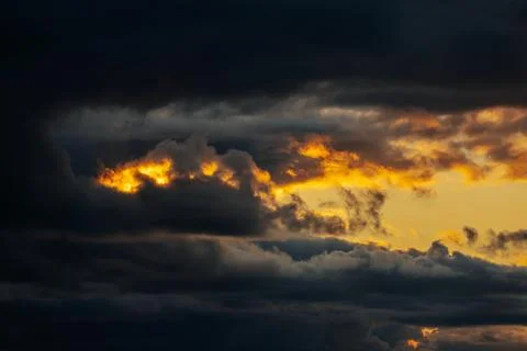 Dramatic sunset clouds with vibrant orange and yellow hues contrasting agai.. Stock Photos