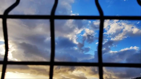 Dramatic Sunset Clouds Viewed Through Metal Chain Link Fence - 4K Video stock 334628203