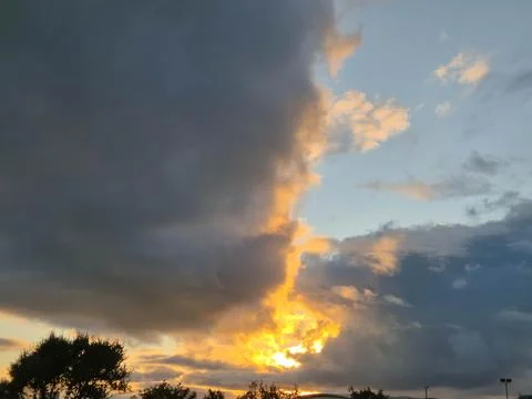 Dramatic sunset clouds with warm light streaks in sky Stock Photos