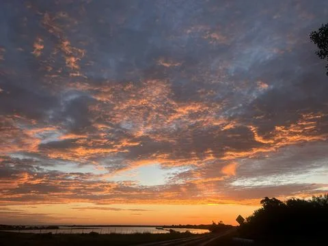 Dramatic Sunset Cloudscape Over Lake and Rural Road Fotos Stock