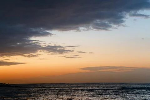 Dramatic Sunset Coastline with Golden Light Over Calm Ocean Horizon Stock Photos