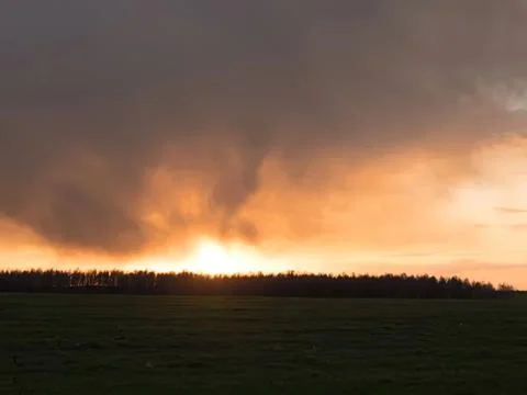 Dramatic sunset with dark storm clouds over open field Stock Photos