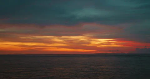 Dramatic sunset glow painting clouds orange yellow red dark stormy sky over vast Stock Footage 327792577