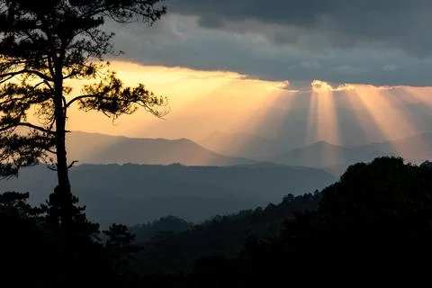 Dramatic sunset with godlight shining through the cloudy sky. Stock Photos