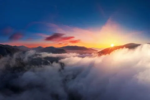 Dramatic sunset high in the mountains above the clouds from aerial view. Stock Photos