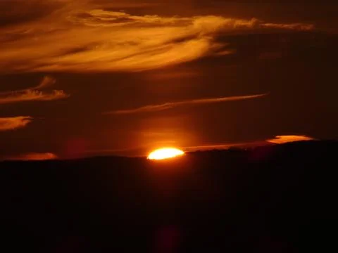 Dramatic sunset just as the sun dips below a dark horizon Stock Photos