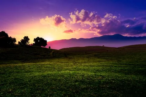 Dramatic sunset landscape with meadow and mountain. Stock Photos