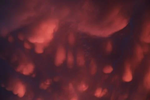 Dramatic sunset landscape with puffy clouds lit by orange setting sun and blu Stock Photos