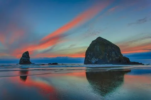 Dramatic sunset light in clouds over beach and rock formations on the Oregon coa Stock Photos