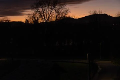 Dramatic sunset with lilac orange clouds over bar trees and hills in winterti Stock Photos