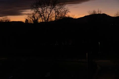 Dramatic sunset with lilac orange clouds over bar trees and hills in winterti Stock Photos