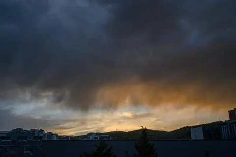 Dramatic sunset or sunrise over city with thick layer of dark storm clouds .. Stock-Fotos