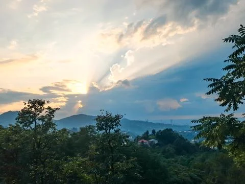 A dramatic sunset or sunrise with sunbeams radiating through clouds over a lu Fotos Stock