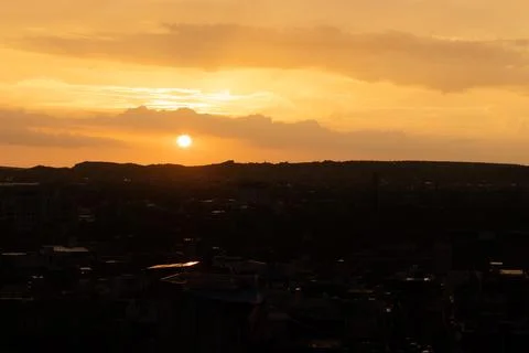 Dramatic sunset orange sky with city backlit view from mountain top at evenin Stockfoto's