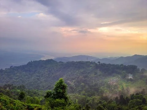 Dramatic sunset orange sky over mountain range and green forest at evening fr 库存照片