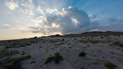 Dramatic sunset over arid desert hills and sandy shrubs Foto stock
