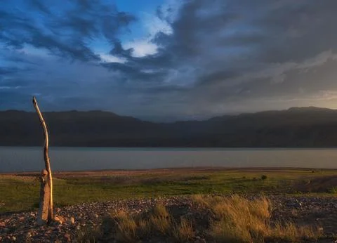 Dramatic sunset over Bartogay reservoir with stormy clouds and golden light o Stock Photos