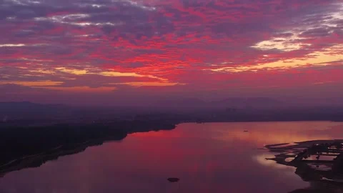 Dramatic sunset over calm lake with red clouds and mountain silhouette Stock Footage 341924920
